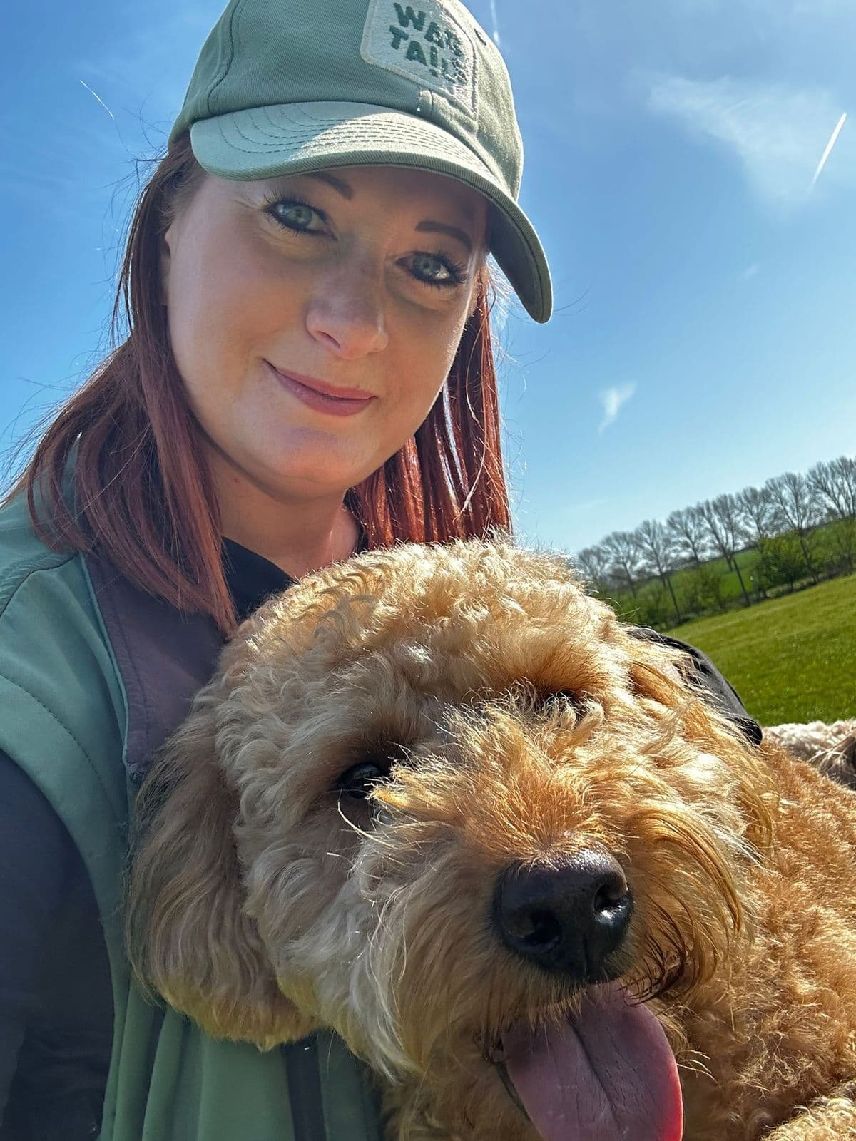 Wagtails staff member wearing branded cap taking a selfie with a Goldendoodle